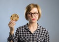 Young blond cute and friendly caucasian woman in casual clothes holding big delicious chocolate cookie Royalty Free Stock Photo