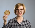 Young blond cute and friendly caucasian woman in casual clothes holding big delicious chocolate cookie Royalty Free Stock Photo