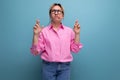 young blond european woman model with ponytail hairstyle in a stylish look consisting of a pink shirt and denim pants is Royalty Free Stock Photo