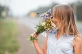 Young blond girl enjoys the aroma of a bouquet of wildflowers