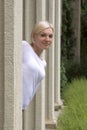 Young blond girl looks out from behind a column