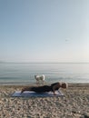 Young blond girl practice plank pose with her dog on sea shore at sunrise