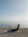 Young blond girl practice upward facing dog yoga asana on sea shore at sunrise