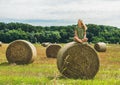 Young blond girl sitting on haystack and smiling, Hungary