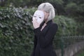 Young blond girl taking off a mask. Pretending to be someone else concept. outdoors.