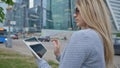 A young blond girl uses a tablet on a background of skyscrapers downtown.