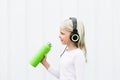 Blond girl on white background drink fresh spring water from green reusable bottle. Healthy lifestyle in summer city