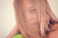 A young blond hair girl portrait with messy hair. A teenager is hiding the photographer behind her long hair