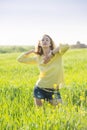 Young blond hair woman poses in a summer green wheat field