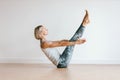 young blond hair woman in yoga pose Paripurna Navasana or Full boat Pose on white wall background Royalty Free Stock Photo