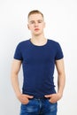 Young blond handsome man in blue shirt and jeans poses