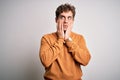 Young blond handsome man with curly hair wearing casual sweater over white background Tired hands covering face, depression and Royalty Free Stock Photo