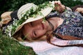 Young blond hippie women, wearing colorful boho style clothes and straw hat, lying, relaxing on green grass of field on sunny Royalty Free Stock Photo