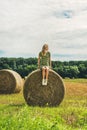 Young blond lady sitting on haystack and looking away, Hungary