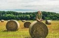 Young blond lady sitting on haystack and smiling, Hungary