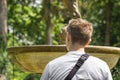 Young blond lonely man sitting on bench in summer city park. Back view. Tourist in white t-shirt thinking about life. Royalty Free Stock Photo