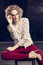 A young blond man androgyne in the image of an attractive woman dressed in a floral shirt,