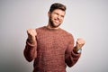 Young blond man with beard and blue eyes wearing casual sweater over white background very happy and excited doing winner gesture Royalty Free Stock Photo