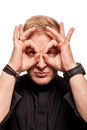 Young blond man in a black shirt, watches and bracelet is making faces, isolated on a white background Royalty Free Stock Photo