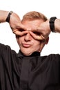 Young blond man in a black shirt, watches and bracelet is making faces, isolated on a white background Royalty Free Stock Photo