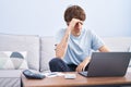 Young blond man stressed using laptop sitting on sofa at home Royalty Free Stock Photo