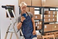 Young blond man using smartphone working at storehouse depressed and worry for distress, crying angry and afraid Royalty Free Stock Photo