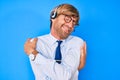 Young blond man wearing call center agent headset hugging oneself happy and positive, smiling confident Royalty Free Stock Photo