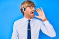 Young blond man wearing call center agent headset shouting and screaming loud to side with hand on mouth Royalty Free Stock Photo