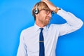 Young blond man wearing call center agent headset surprised with hand on head for mistake, remember error Royalty Free Stock Photo