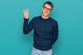 Young blond man wearing casual clothes and glasses showing and pointing up with fingers number three while smiling confident and Royalty Free Stock Photo