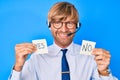 Young blond man wearing operator headset holding yes and no reminder smiling with a happy and cool smile on face Royalty Free Stock Photo