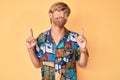 Young blond man wearing summer shirt pointing up looking sad and upset, indicating direction with fingers, unhappy and depressed Royalty Free Stock Photo