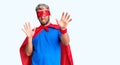 Young blond man wearing super hero custome afraid and terrified with fear expression stop gesture with hands, shouting in shock