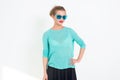 Young blond model posing in studio, performing new fashion glamour look, wearing sunglasses, putting her arm on the hip Royalty Free Stock Photo