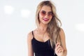 Young blond model presenting new fashionable summer look, wearing circle sunglasses, red skirt and black sleeveless top Royalty Free Stock Photo