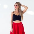 Young blond model presenting new fashionable summer look, wearing circle sunglasses, red skirt and black sleeveless top Royalty Free Stock Photo