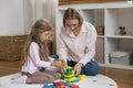 Young blond mother play wooden cubes with little cute daughter