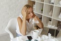 Young blond pretty sick with flu businesswoman sitting at her working place holding white napkins. Sick freelancer concept.