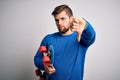 Young blond skeater man with beard and blue eyes holding skate over white background with angry face, negative sign showing Royalty Free Stock Photo