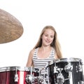 Young blond teenage girl plays the drums in studio against white Royalty Free Stock Photo