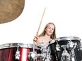 Young blond teenage girl plays the drums in studio against white Royalty Free Stock Photo