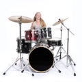 Young blond teenage girl plays the drums in studio against white Royalty Free Stock Photo