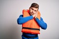 Young blond tourist man with beard and blue eyes wearing lifejacket over white background sleeping tired dreaming and posing with Royalty Free Stock Photo