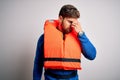 Young blond tourist man with beard and blue eyes wearing lifejacket over white background tired rubbing nose and eyes feeling Royalty Free Stock Photo