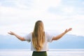 Young blond woman with arms wide open enjoy landscape of cloudy mountains Royalty Free Stock Photo