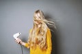 Young blond woman blow-drying her hair