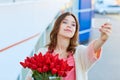 Young blond woman with a bouquet of red tulips is taking selfie Royalty Free Stock Photo