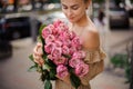 Young blond woman carefully holds big bouquet of light pink roses and looks at it Royalty Free Stock Photo