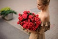 Young blond woman holds large beautiful bouquet of red roses. Royalty Free Stock Photo