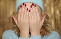 Young blond woman covering her face